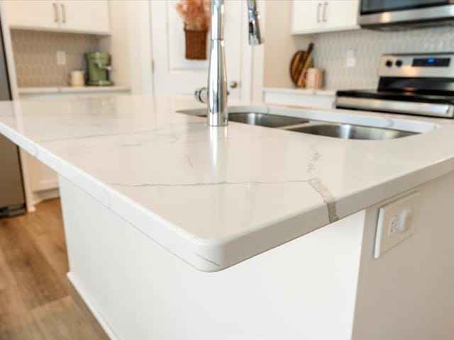 kitchen featuring light stone counters, light wood-style flooring, stainless steel electric stove, and white cabinets