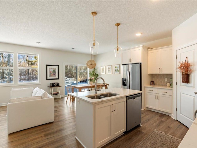 kitchen featuring dark wood-style flooring, appliances with stainless steel finishes, a sink, white cabinetry, and decorative light fixtures