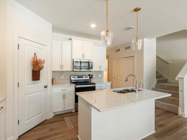 kitchen featuring dark wood-type flooring, a sink, decorative backsplash, and appliances with stainless steel finishes