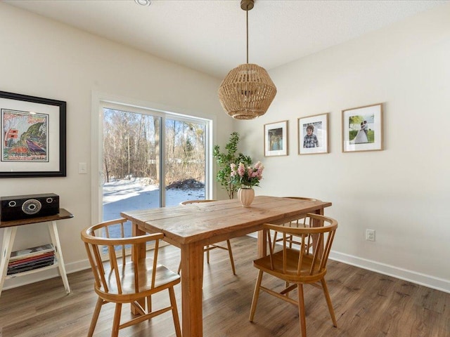 dining area with baseboards, wood finished floors, and an inviting chandelier
