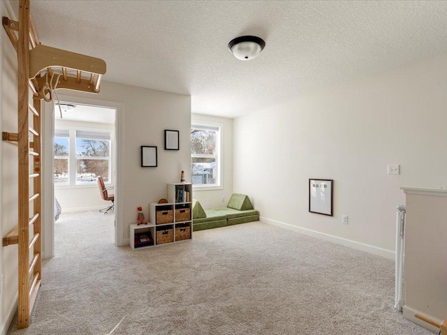living area with carpet flooring, a textured ceiling, and a wealth of natural light