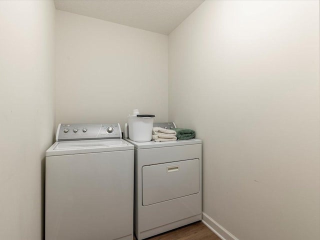 laundry area featuring laundry area, baseboards, wood finished floors, and washing machine and clothes dryer