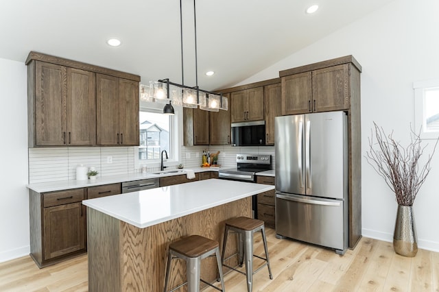 1812 Brandt Dr NE, Byron, MN 55920 - kitchen with appliances with stainless steel finishes, tasteful backsplash, vaulted ceiling, a center island, and light countertops