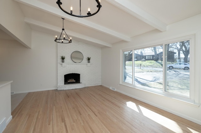 unfurnished living room featuring an inviting chandelier, a brick fireplace, vaulted ceiling with beams, wood finished floors, and visible vents