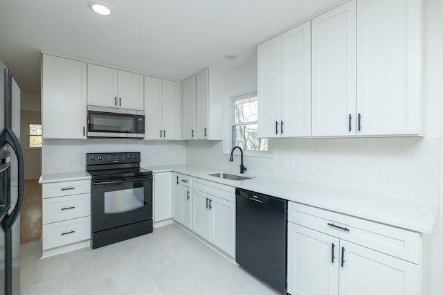 kitchen featuring tasteful backsplash, a sink, light countertops, white cabinets, and black appliances