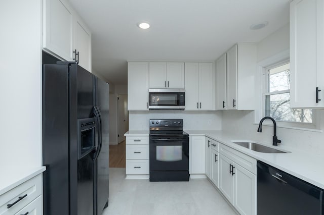 kitchen featuring a sink, light countertops, white cabinets, black appliances, and light floors