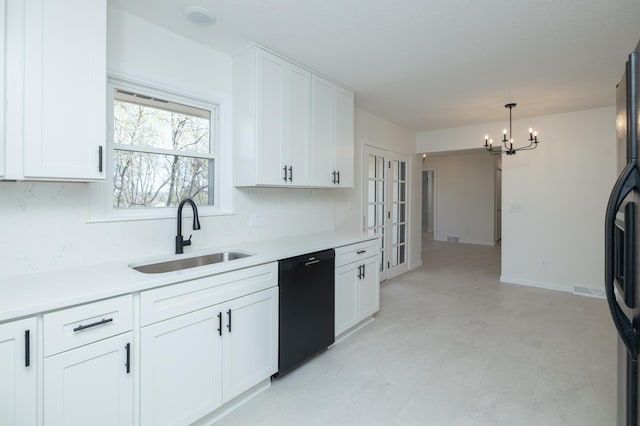 kitchen with black appliances, light countertops, white cabinets, a sink, and a notable chandelier