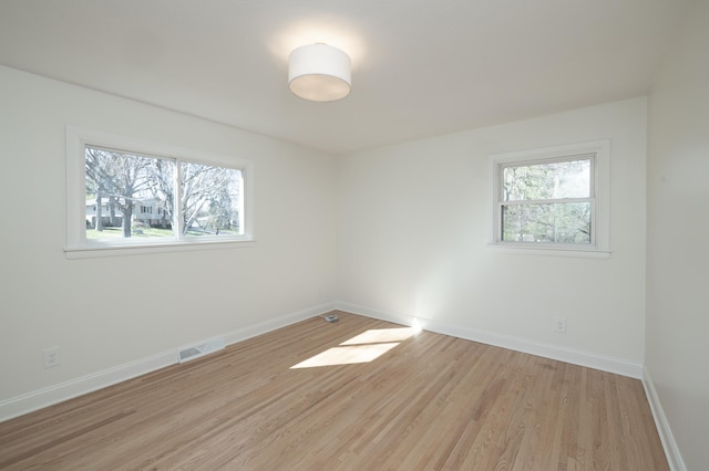 unfurnished room featuring a wealth of natural light, light wood finished floors, and visible vents