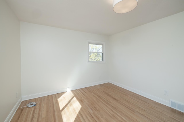 spare room featuring baseboards, visible vents, and light wood-style flooring