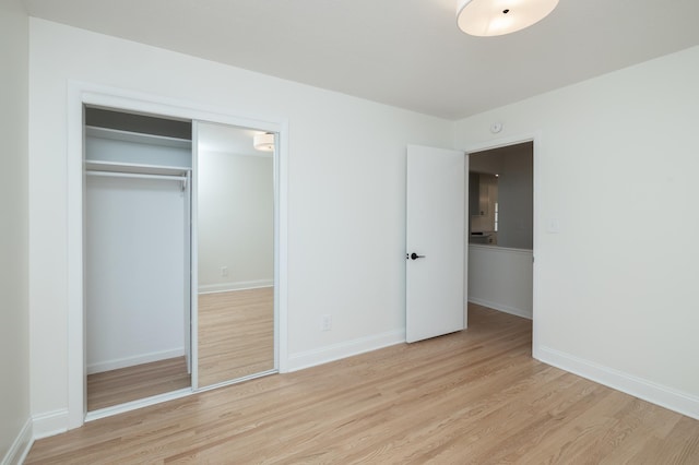 unfurnished bedroom featuring baseboards, a closet, and light wood-style flooring