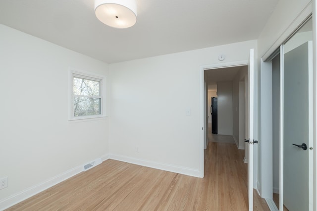 spare room featuring light wood-style floors, baseboards, and visible vents