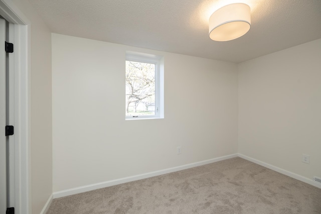 carpeted empty room with baseboards and a textured ceiling