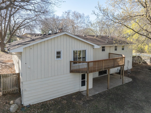 rear view of house with fence, a shingled roof, a patio area, and a wooden deck