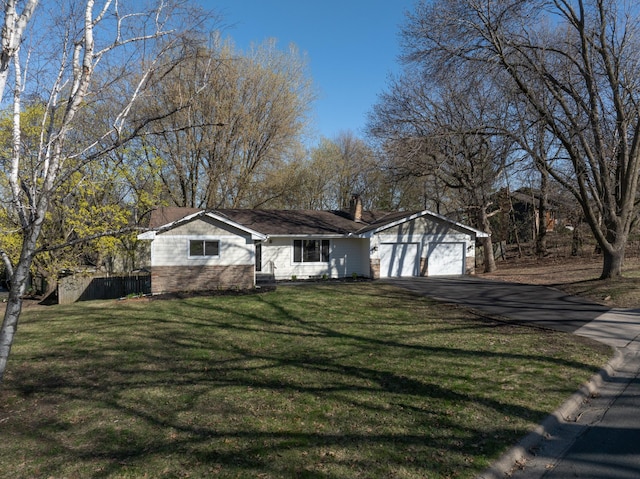 ranch-style home featuring a front lawn, a chimney, brick siding, an attached garage, and driveway