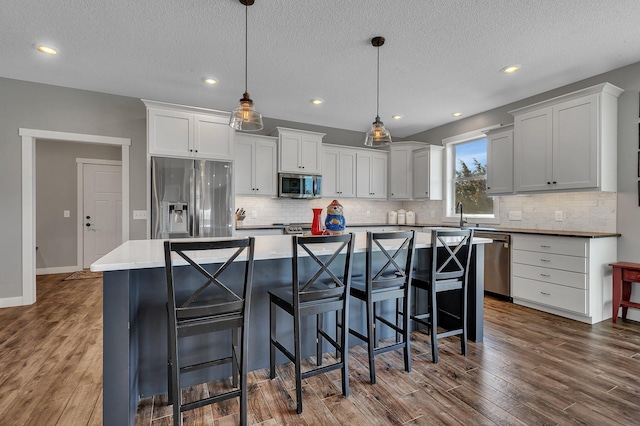 8619 State Highway 55 NW, Annandale, MN 55302 - kitchen featuring appliances with stainless steel finishes, backsplash, dark wood-style flooring, and a textured ceiling