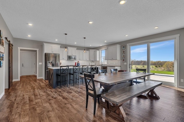 8619 State Highway 55 NW, Annandale, MN 55302 - dining room featuring baseboards, dark wood-style floors, recessed lighting, a barn door, and a textured ceiling