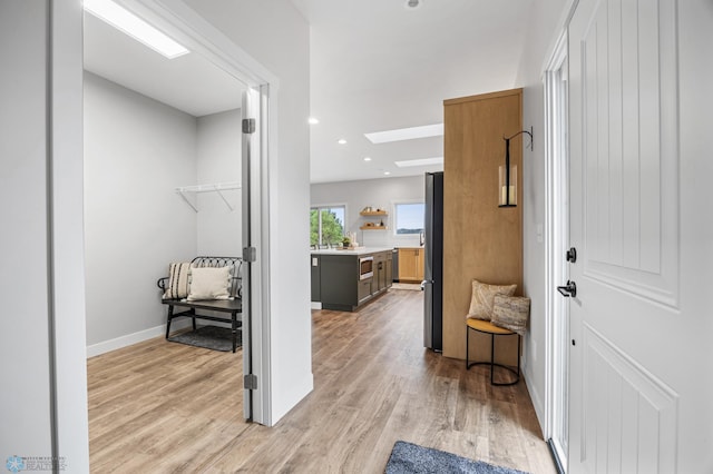 interior space with light wood-style floors, baseboards, a skylight, and recessed lighting