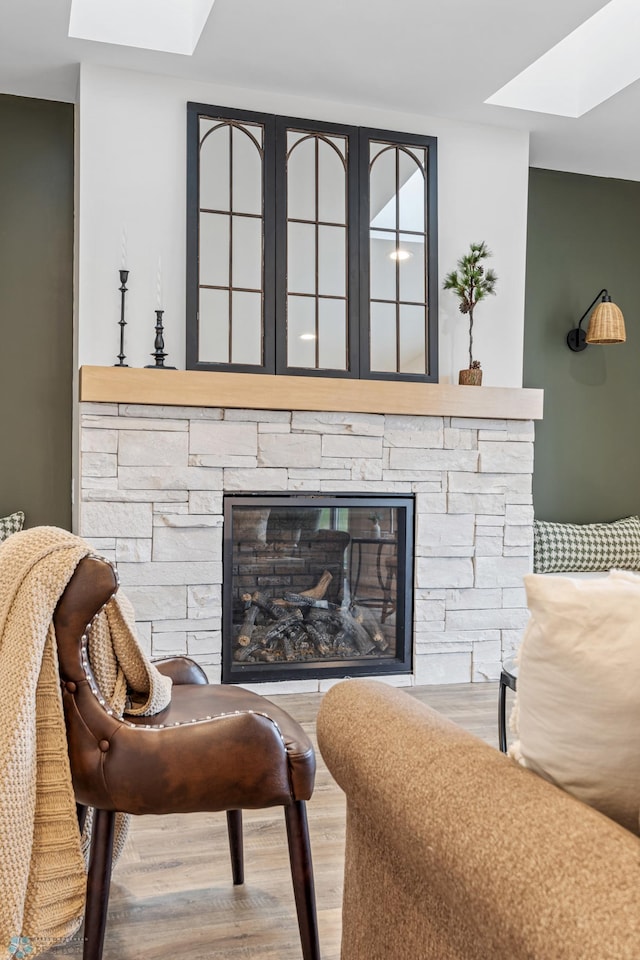 living area with a skylight, a fireplace, and wood finished floors