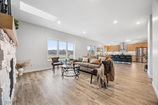 living room with baseboards, recessed lighting, a skylight, and light wood-style flooring