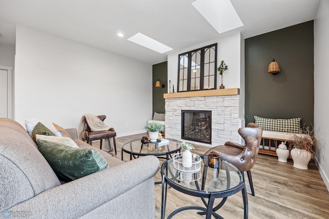 living area with baseboards, a fireplace, wood finished floors, and a skylight