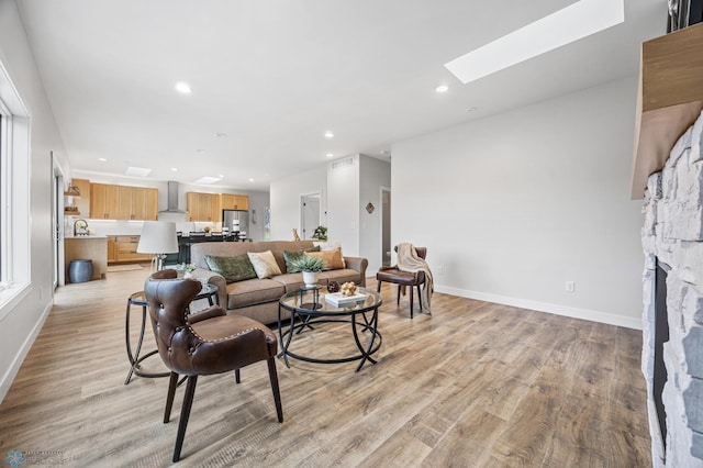 living area featuring baseboards, a skylight, and light wood-style flooring