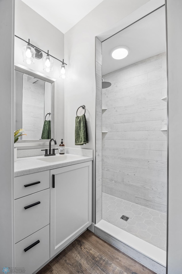 full bathroom with vanity, wood finished floors, and tiled shower