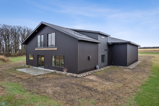 rear view of property with a patio and roof with shingles