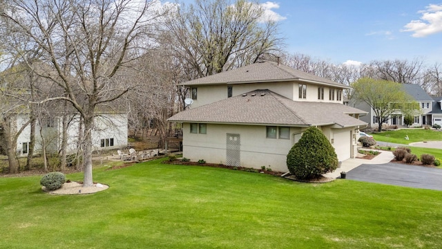 view of property exterior featuring aphalt driveway, a lawn, roof with shingles, stucco siding, and an attached garage