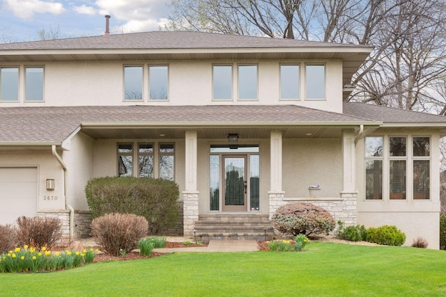 prairie-style house featuring covered porch, stucco siding, a front yard, and stone siding
