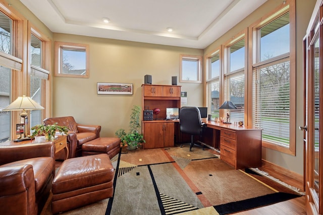 office area featuring baseboards, light wood-style flooring, a raised ceiling, and recessed lighting