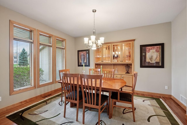 dining area with baseboards, visible vents, light wood finished floors, and a notable chandelier