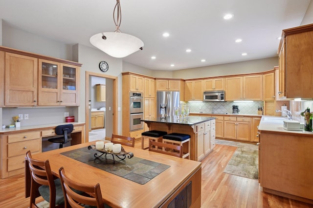 kitchen with a kitchen island, built in study area, light wood finished floors, stainless steel appliances, and recessed lighting