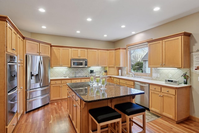 kitchen featuring appliances with stainless steel finishes, a kitchen breakfast bar, light wood-style flooring, a center island, and recessed lighting