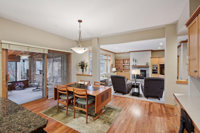 dining space featuring baseboards, light wood-style flooring, and a tile fireplace