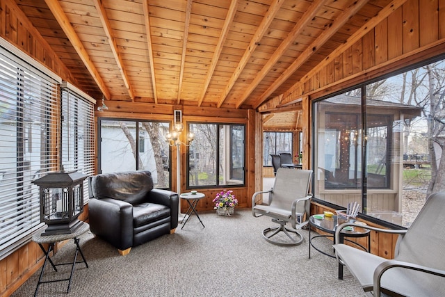sunroom with lofted ceiling with beams, wood ceiling, carpet flooring, and wood walls