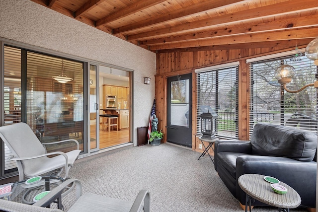 sunroom featuring carpet floors, wood walls, wooden ceiling, and beam ceiling
