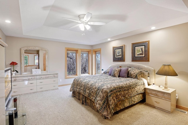 bedroom with visible vents, a raised ceiling, baseboards, and light carpet