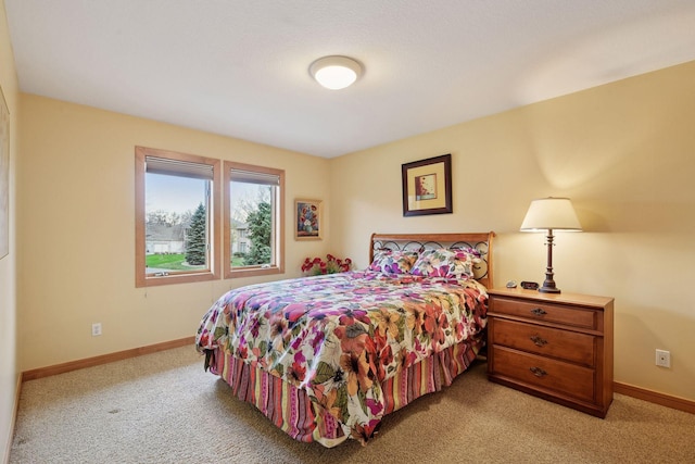bedroom with baseboards and light carpet