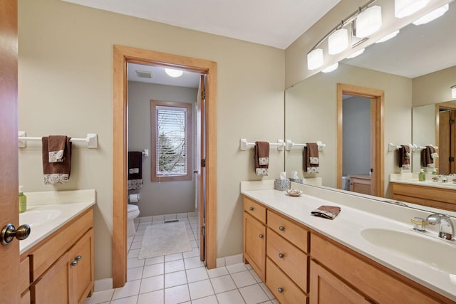 full bathroom with toilet, baseboards, tile patterned floors, two vanities, and a sink