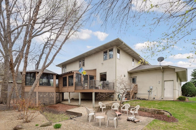rear view of house with a sunroom, stucco siding, stairs, and a deck