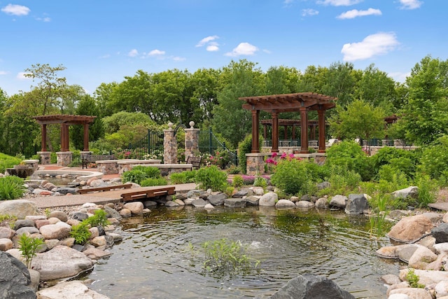 view of yard featuring a pergola and a small pond