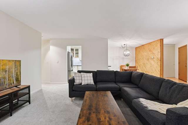 living room featuring baseboards, a chandelier, and light carpet