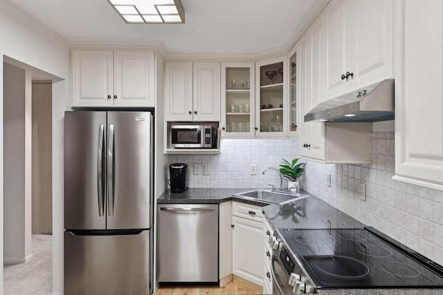 kitchen with a sink, stainless steel appliances, decorative backsplash, under cabinet range hood, and glass insert cabinets