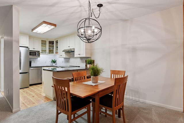 dining space featuring baseboards, a chandelier, and light colored carpet