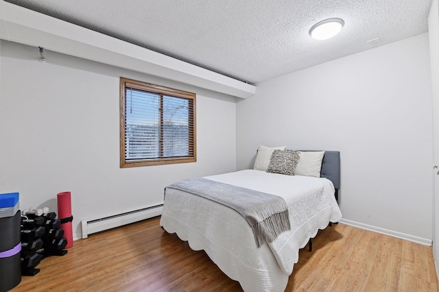 bedroom featuring baseboards, a textured ceiling, wood finished floors, and a baseboard radiator