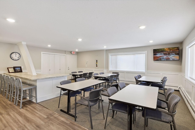 dining space featuring recessed lighting, wainscoting, light wood finished floors, and a baseboard heating unit