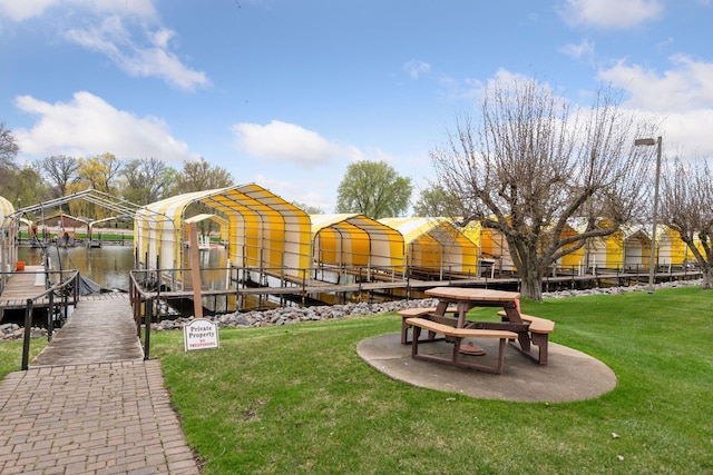 view of property's community with a yard, boat lift, a water view, and a boat dock
