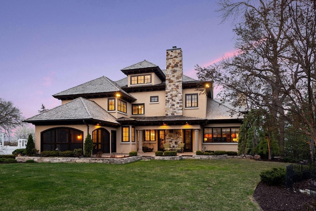 back of property with a patio area, stucco siding, a yard, and a chimney