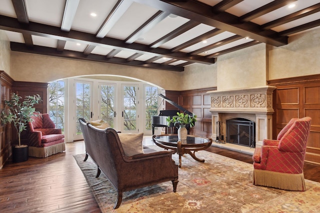 living room featuring beamed ceiling, wood-type flooring, a glass covered fireplace, a decorative wall, and recessed lighting