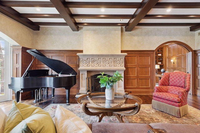 living area with wood finished floors, arched walkways, and beam ceiling